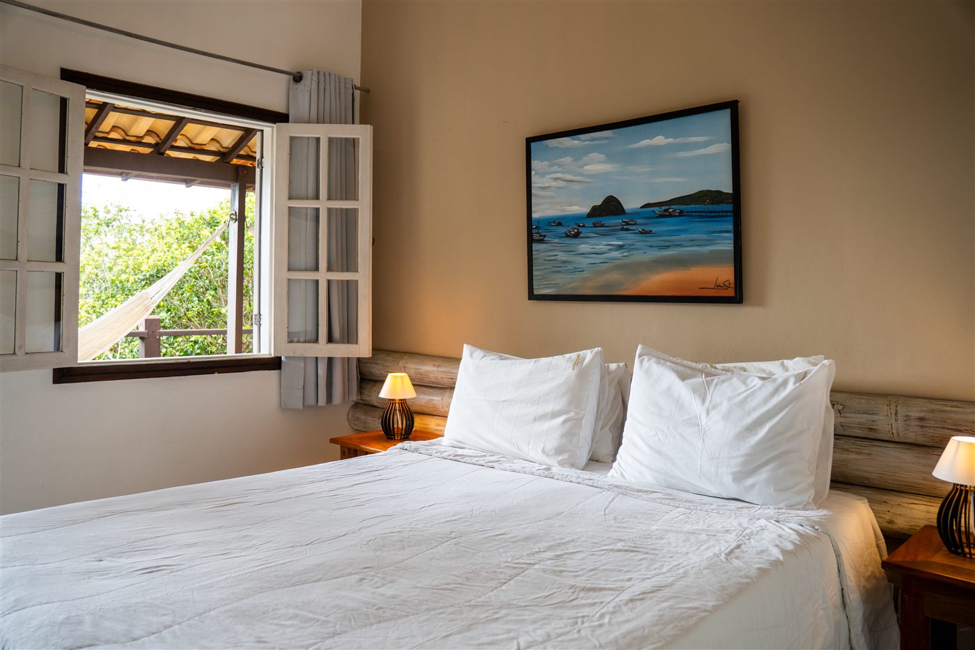 Suíte confortável da Pousada Vila Pitanga com cama de casal e vista para a mata